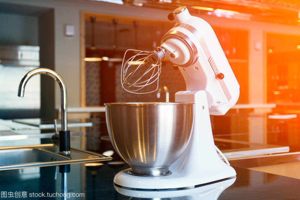 一个美丽的白色搅拌机与金属杯站在现代厨房